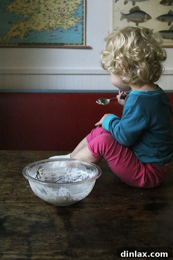 A child, Tig, happily eating a bowl of apple pie overnight oats.