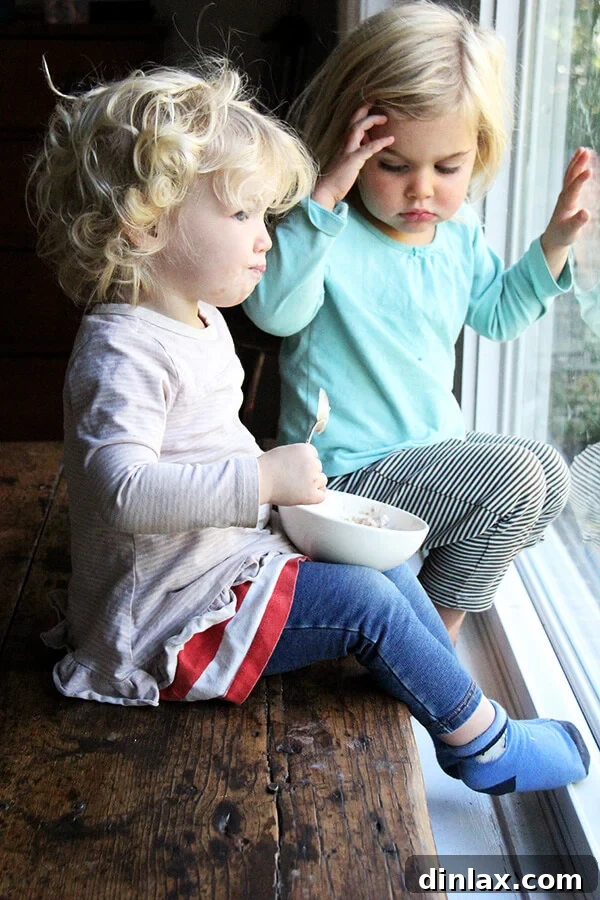 Two children, Tig and Wren, enjoying their breakfast of apple pie overnight oats.