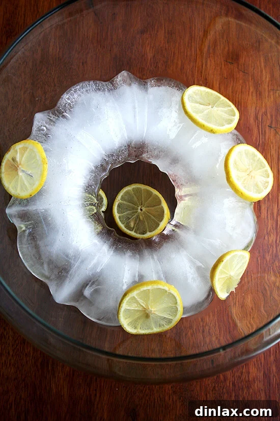 The punch bowl, now adorned with the substantial ice ring and artfully arranged slices of fresh lemon, creating an inviting presentation.