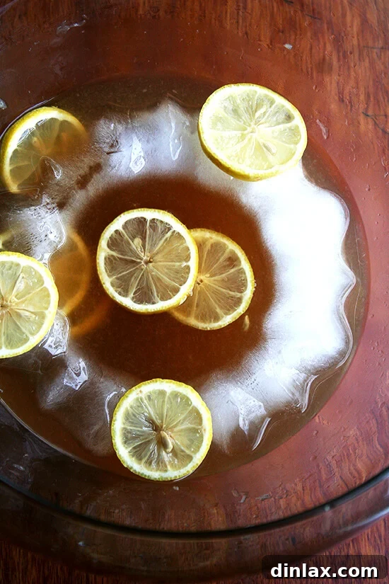 A vibrant punch bowl generously filled with the iconic Philadelphia Fish House Punch, featuring the elegant ice ring and bright lemon slices as garnish, inviting guests to serve themselves.