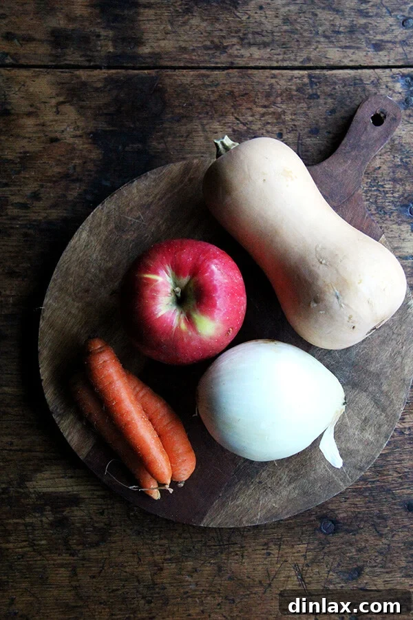 Autumn Glow Butternut Apple Slow Cooker Soup 3 A board of ingredients: apple, onion, carrots, and butternut squash.