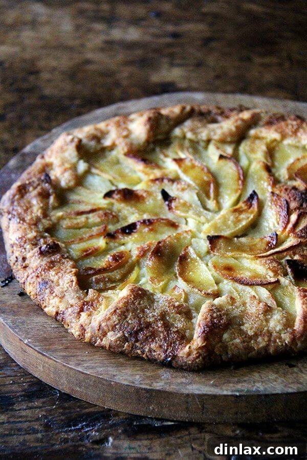 A freshly baked apple-frangipane galette resting on a wooden serving board.