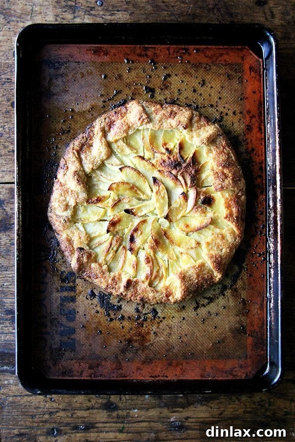 Just baked apple-frangipane galette cooling on a sheet pan, showcasing its golden crust.