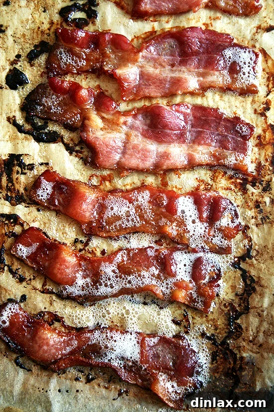 Perfectly cooked, crispy bacon strips resting on parchment paper after roasting
