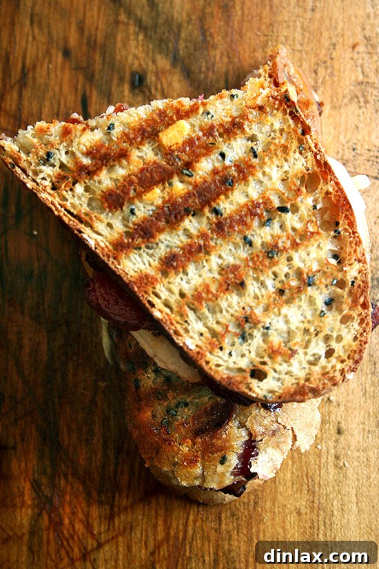 A finished bacon, cheddar, and pear panini on a wooden cutting board, ready to be enjoyed