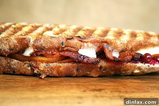 Two halves of a delicious bacon, pear, and cheddar panini, stacked and ready to eat