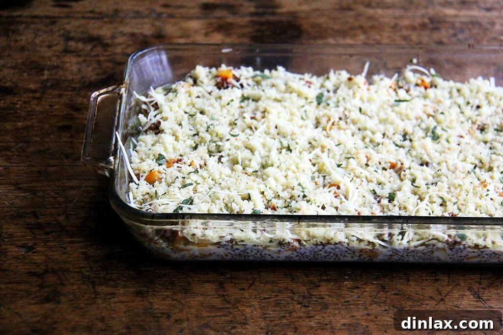 A 9x13-inch baking dish filled with the unbaked quinoa mixture, topped with an even layer of cheese, illustrating the dish prepared and ready for the oven.