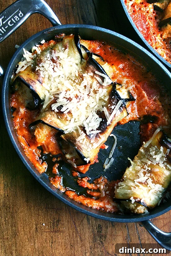 A pan of eggplant involtini with one serving removed, revealing the cheesy interior.