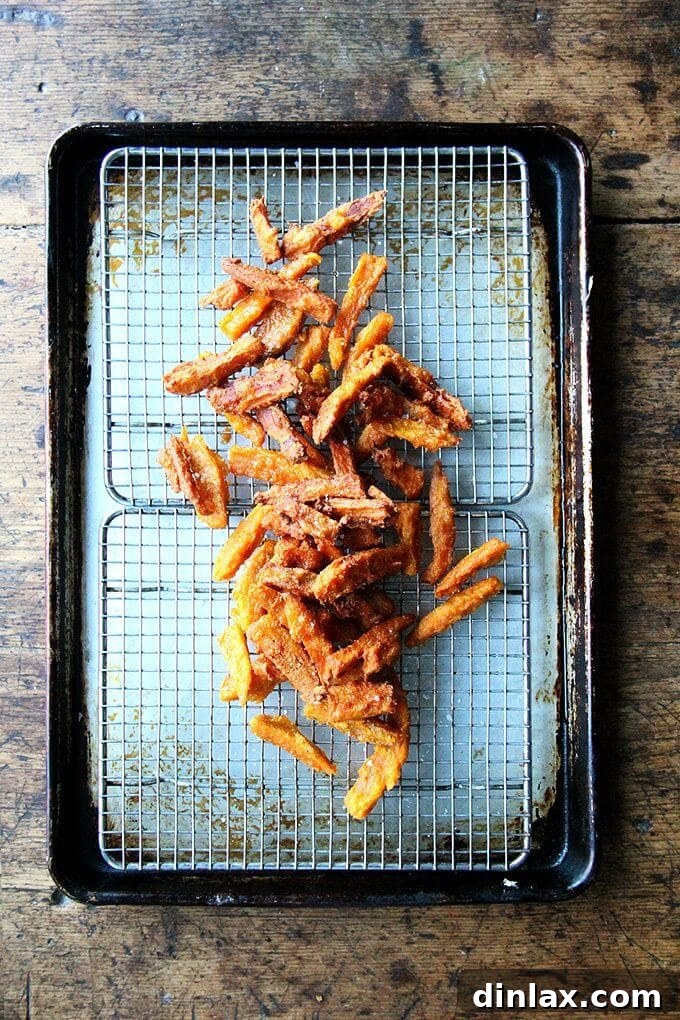 A tray of just fried thick-cut sweet potato fries, perfectly golden and crispy.