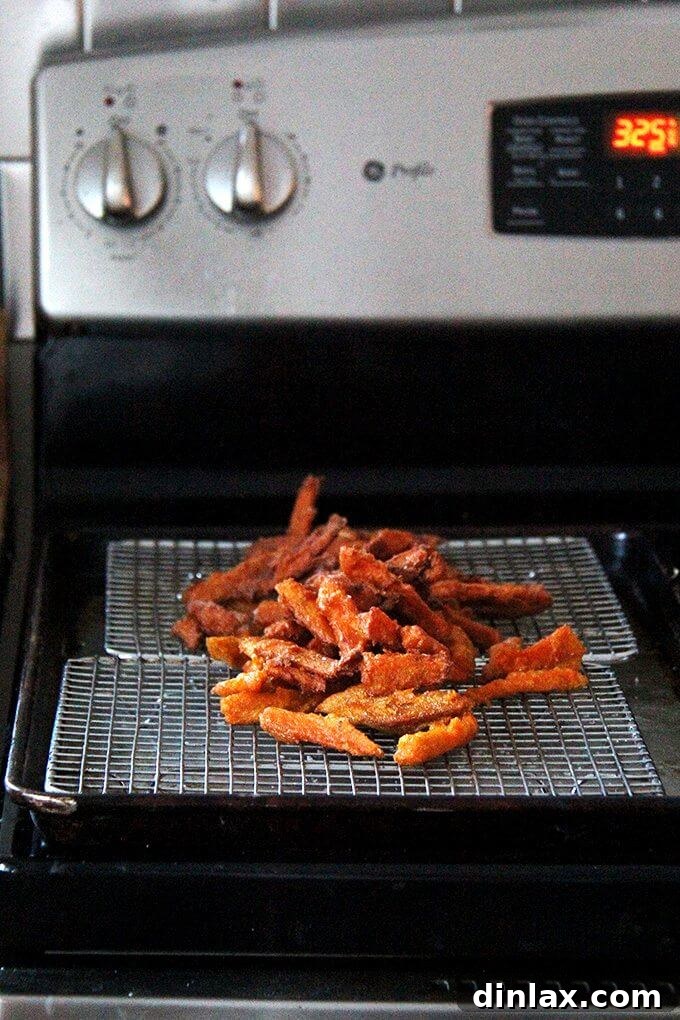 A close-up of a pile of perfectly fried sweet potato wedges, showing their golden brown color and crispy texture.
