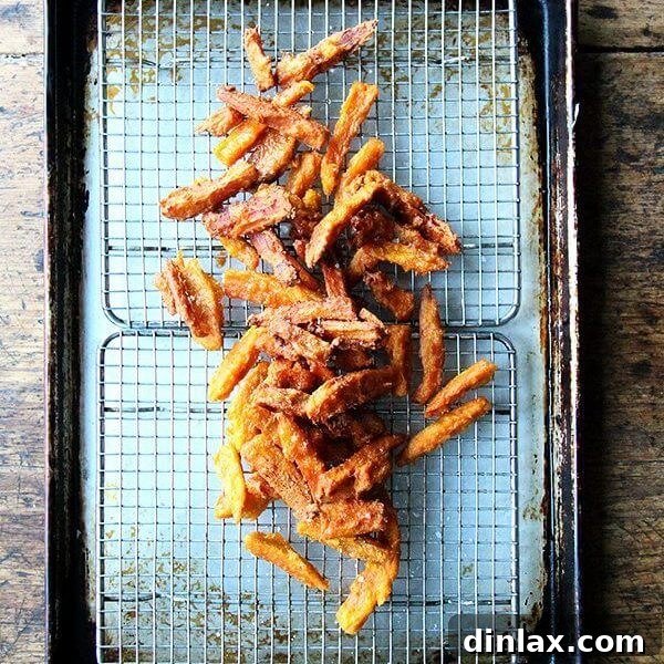 A tray of just fried thick-cut sweet potato fries, perfectly golden and crispy.