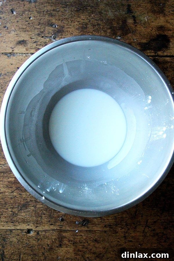 A bowl containing the cornstarch and water slurry, showing its smooth, milky consistency.