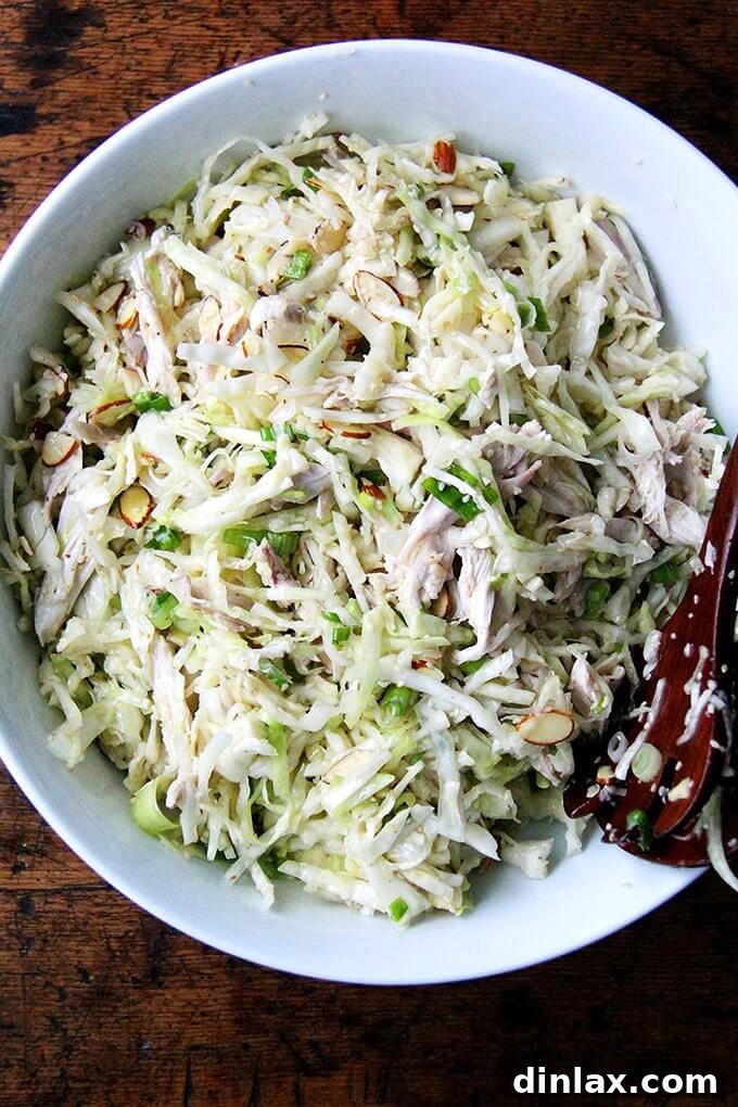 Asian-Inspired Sesame Almond Chicken Slaw 2 A vibrant and generously sized bowl of homemade chicken and cabbage salad, featuring a mix of shredded chicken, crisp green cabbage, and a scattering of sesame seeds, scallions, and sliced almonds, all glistening with a citrus-Asian dressing.