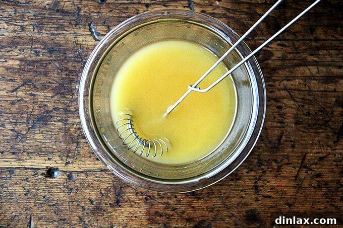 Asian-Inspired Sesame Almond Chicken Slaw 6 A small glass bowl filled with the homemade Citrus-Asian dressing, a perfect blend of oils, vinegar, lemon, and seasonings, ready to be poured over the salad.