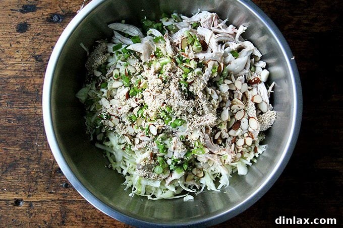 Asian-Inspired Sesame Almond Chicken Slaw 8 A large bowl brimming with all the colorful ingredients for the chicken and cabbage salad – shredded chicken, crisp cabbage, almonds, sesame seeds, and scallions – ready to be tossed with the dressing.
