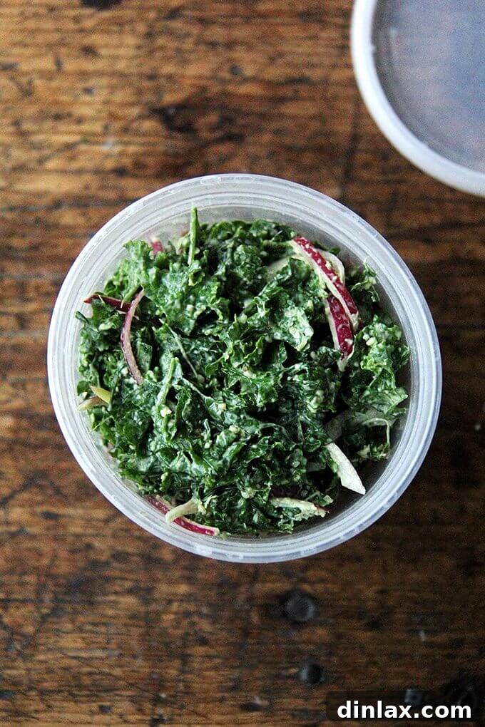 A large bowl filled with vibrant curly kale, dressed with the creamy vegan Caesar dressing and topped with pickled onions and puréed pumpkin seeds.