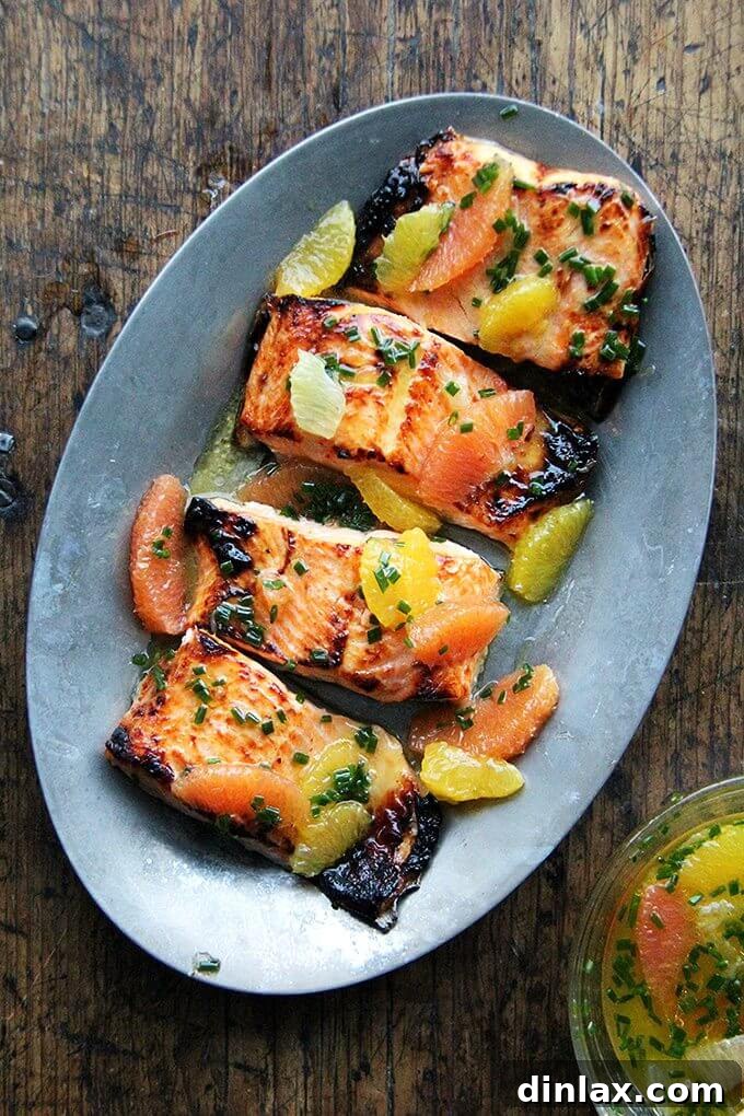 Perfectly broiled Arctic char fillets glistening with a vibrant citrus sauce on a sizzle platter, ready to serve.