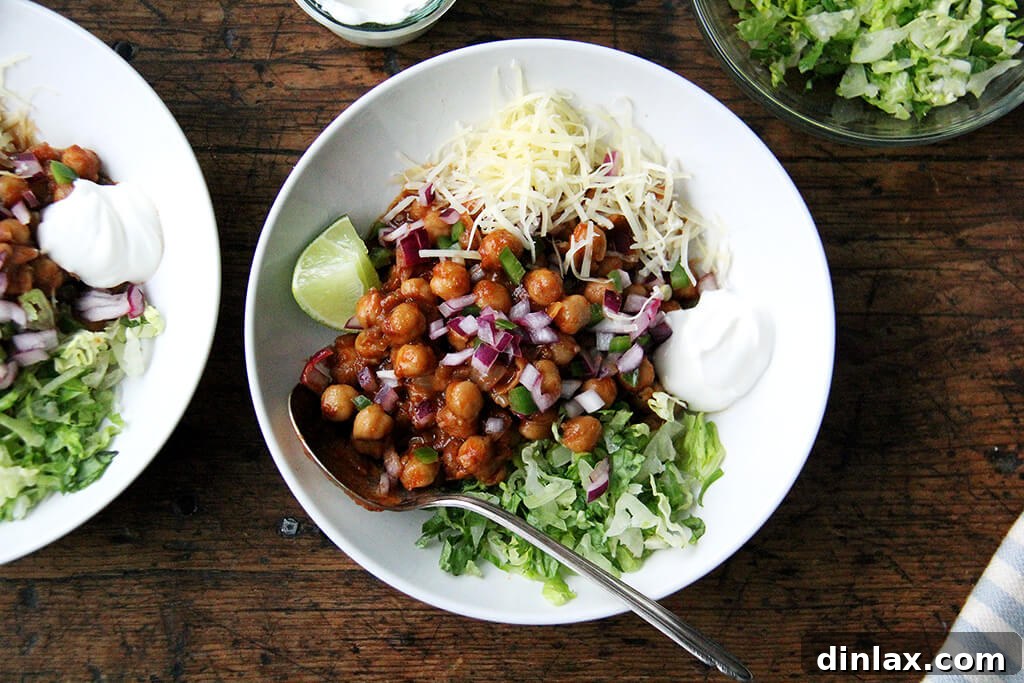 Spiced Chickpea Fiesta Bowls 4 Assembled chickpea taco bowls with lettuce, lime, sour cream, and cheese.