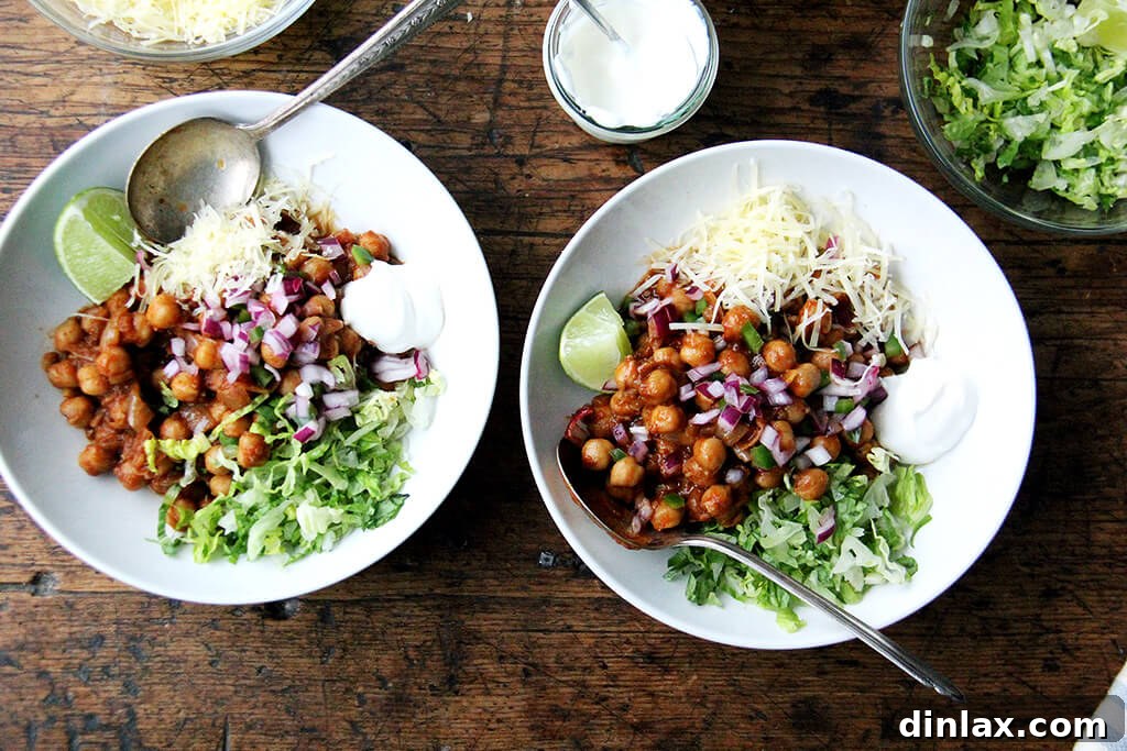 Spiced Chickpea Fiesta Bowls 5 Assembled chickpea taco bowls with lettuce, lime, sour cream, and cheese.