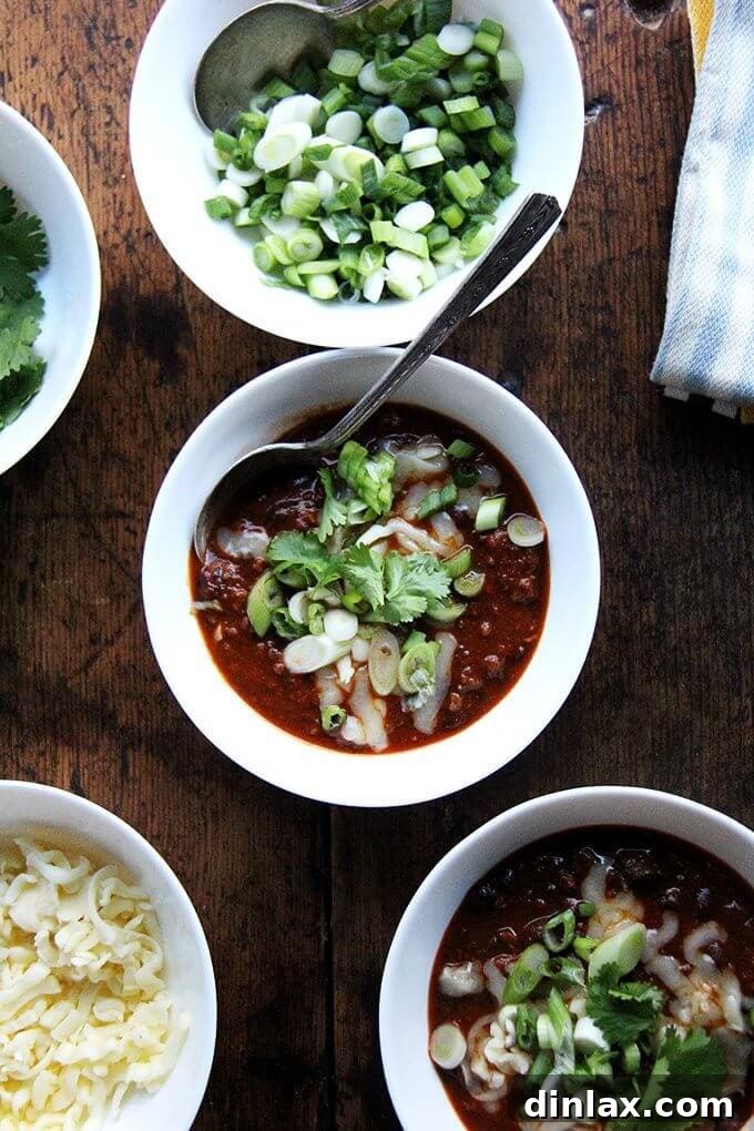 This easy weeknight chili recipe is a crowd-pleaser, perfect for game day, Super Bowl parties, or a simple family dinner. Make it ahead for even better flavor. Hearty bowls of weeknight chili with a variety of fresh toppings, perfect for a cozy meal or gathering.