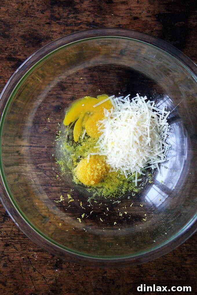 A vibrant bowl of fresh lemon slices and a zester, indicating the importance of fresh lemon in brightening the carbonara dish.