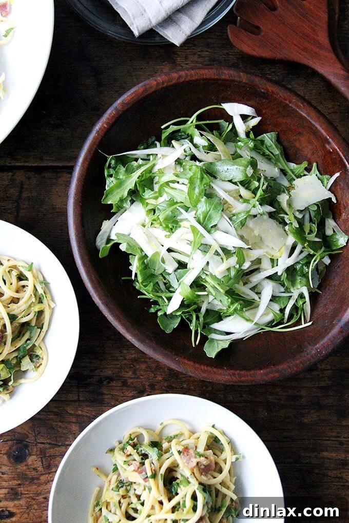 A serving of bucatini carbonara with leeks, lemon, and crispy bacon, showcasing the rich texture and vibrant ingredients.