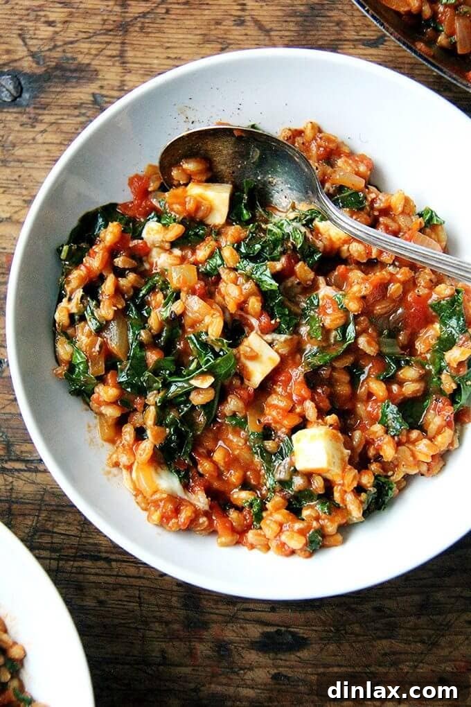 This farro risotto is a one-pot wonder made with water (as opposed to stock), and it's seasoned with thyme, smoked paprika and lemon. I love the greens and cubes of feta gently folded in at the end. // alexandracooks.com A perfectly seasoned bowl of farro risotto with vibrant kale and crumbled feta, ready to be enjoyed.