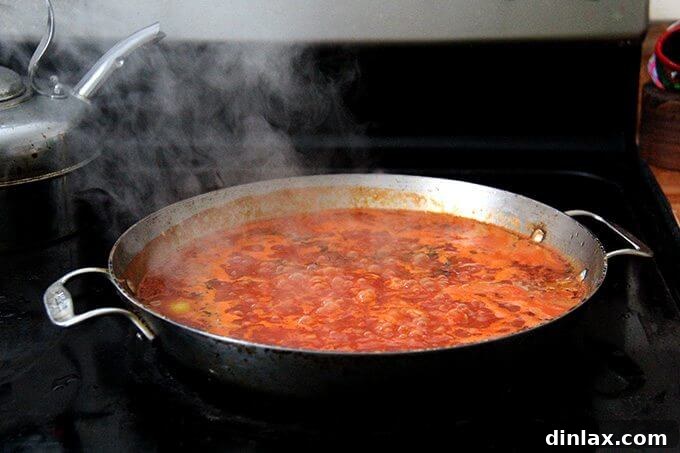 Mediterranean Farro Risotto with Kale and Feta 3 Farro risotto gently simmering on the stovetop in a large sauté pan, absorbing the flavorful liquid.