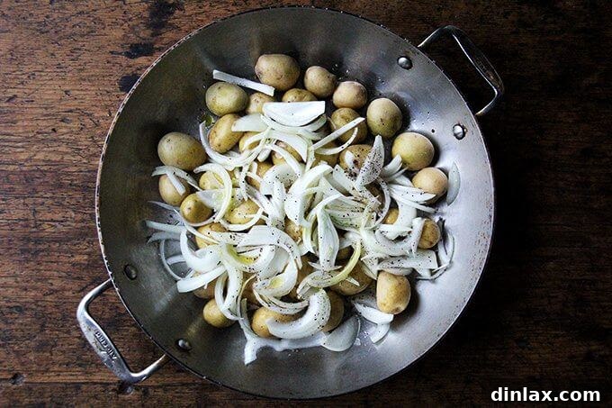 Sheet Pan Tarragon Chicken and Potatoes 4 A braiser filled with diced potatoes and thinly sliced onions, tossed with olive oil, salt, and pepper.