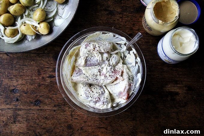 Sheet Pan Tarragon Chicken and Potatoes 5 A bowl of bone-in, skin-on chicken thighs tossed in a creamy mixture of mayonnaise and Dijon mustard.