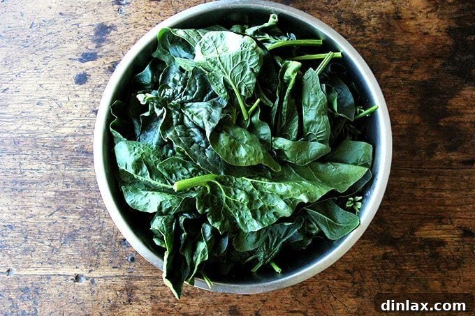 Freshly picked spinach leaves soaking in a bowl of cold water to remove dirt and impurities.