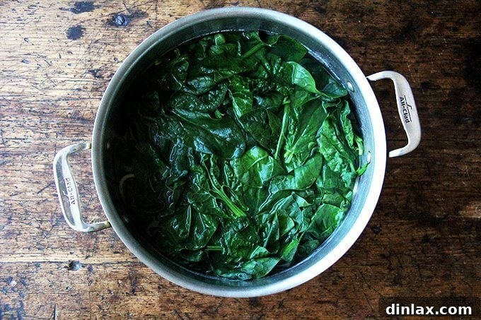 Fresh spinach leaves added to a pot of boiling pasta, just before draining.