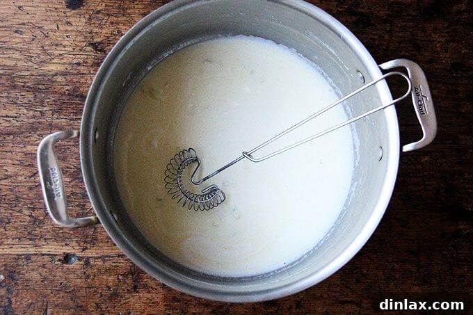 Making the creamy pasta sauce by whisking together butter, crème fraîche, white wine, and reserved pasta water.