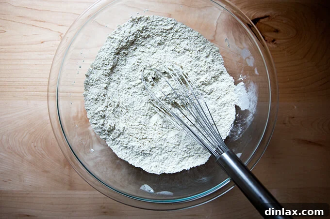 Homemade Bread Made Easy 4 Close-up of a whisk blending the dry ingredients: flour, salt, and yeast, preparing the no-knead bread dough.
