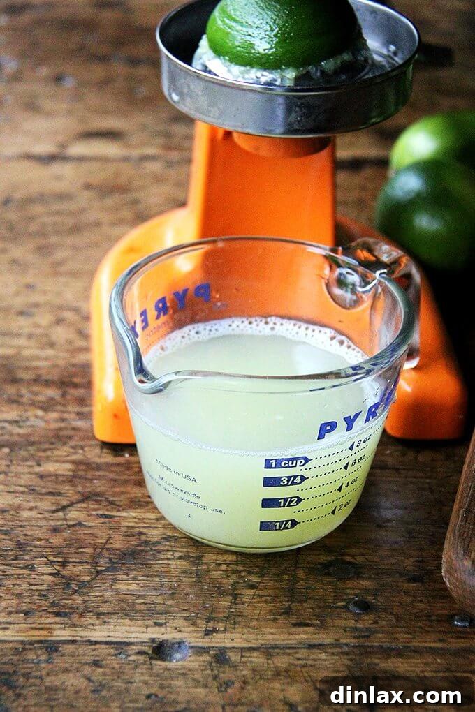 A glass measuring cup filled with vibrant green, freshly squeezed lime juice.