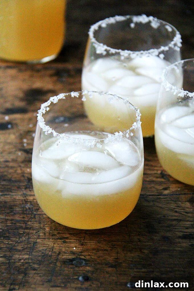 Margaritas served in salted-rim glasses with lime wedges, glistening with ice.