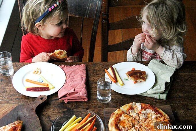 Mastering Skillet Pizza Perfection 2 Two toddlers sitting at a table eating pizza.