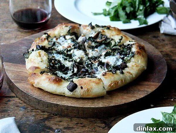 A kale and mushroom skillet pizza on a board.