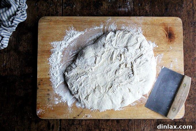 Mastering Skillet Pizza Perfection 8 Pizza dough on a board with flour and a bench scraper.