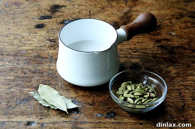 Aromatic Almond Milk Infusion with Cardamom and Bay Leaf for Porridge Almond milk simmering gently in a saucepan, infused with whole cardamom pods and a bay leaf, creating an aromatic base for the healthy breakfast porridge.
