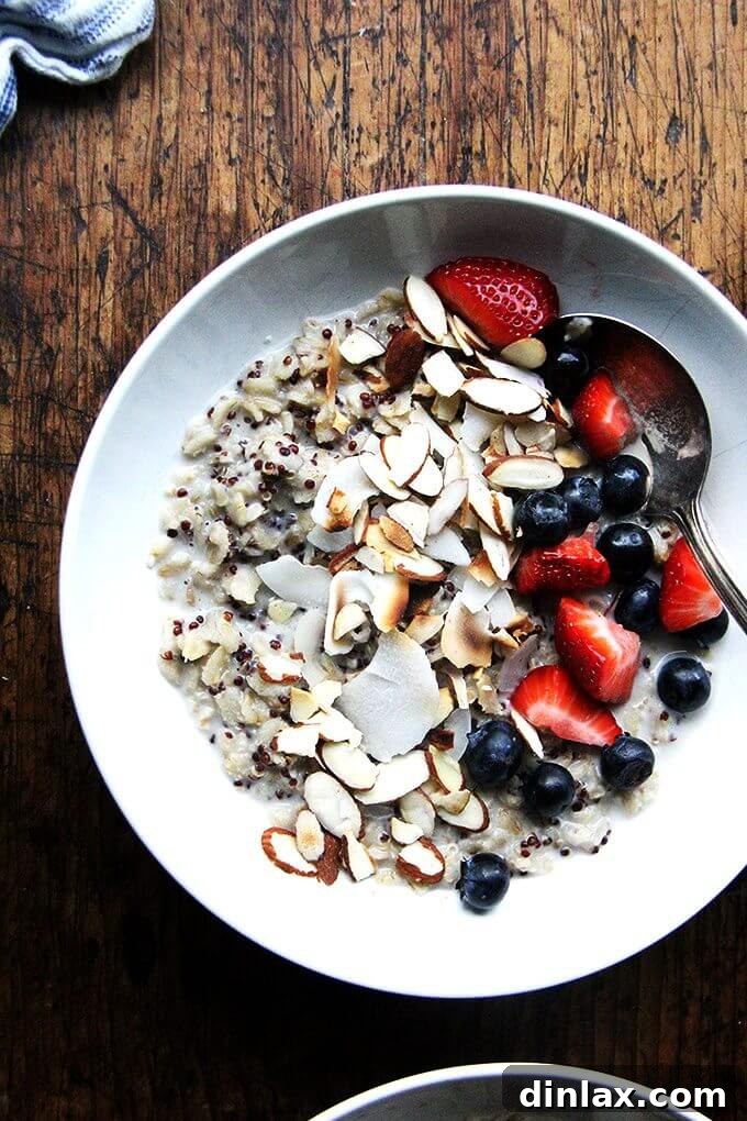 Savoring the Aromatic and Healthy Oat and Quinoa Porridge A close-up shot of a steaming, artfully garnished bowl of Jean Adamson's Oat and Quinoa Porridge, adorned with vibrant fresh berries and crunchy nuts. The image perfectly captures the rich texture and comforting appeal of this healthy, aromatic breakfast, ready to be savored.