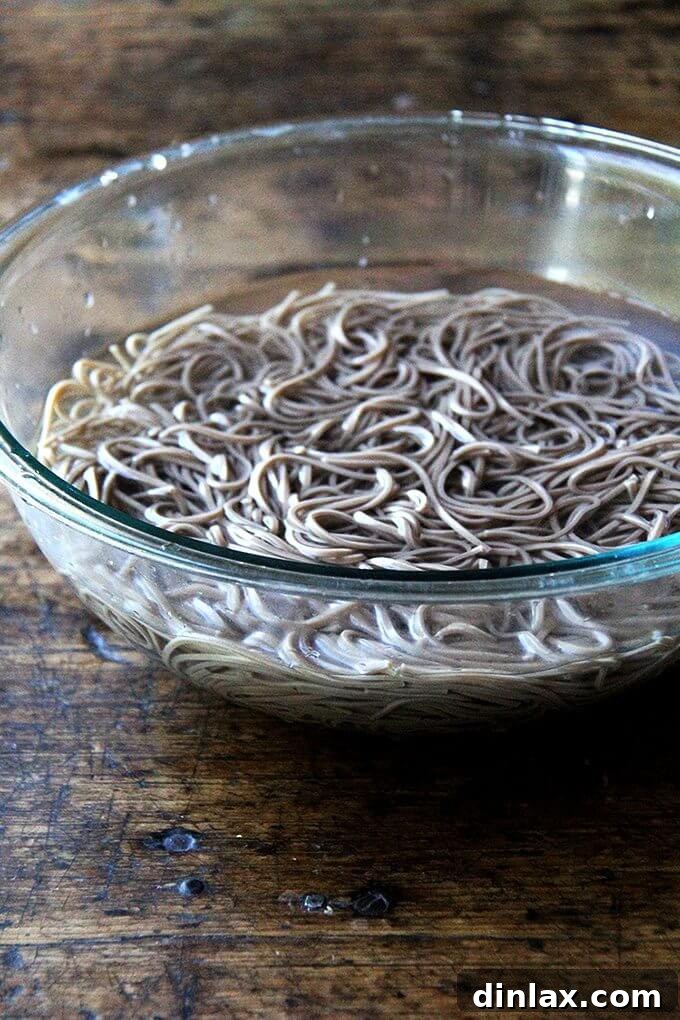 Nutty Sesame Soba Noodles with Tangy Pickled Vegetables 4 Cooked soba noodles are gently cooling in a bowl of cold water, a crucial step to prevent sticking and maintain their perfect al dente texture for the salad.