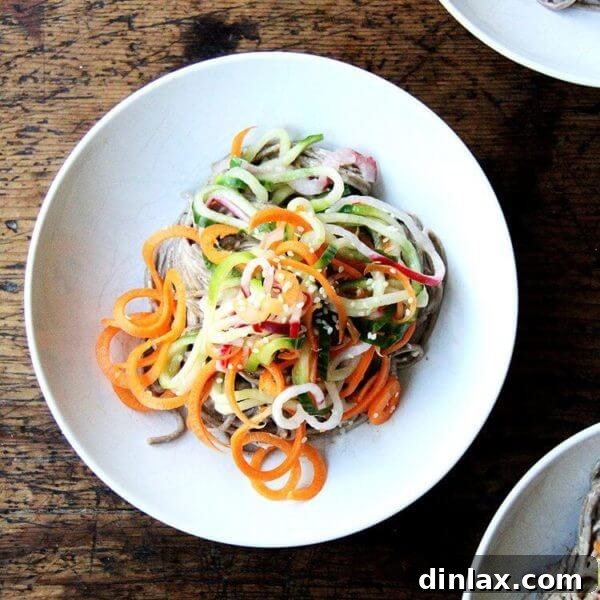 A vibrant bowl of Almond-Sesame Soba Noodles with Quick-Pickled Vegetables, garnished with sesame seeds.
