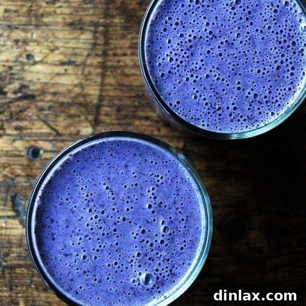 Close-up of a blueberry-almond smoothie in a glass, topped with fresh blueberries.