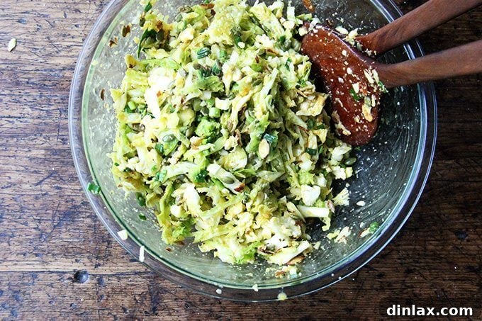 A vibrant cabbage salad with miso-carrot dressing, thoroughly tossed together in a large mixing bowl, showcasing its colorful ingredients.