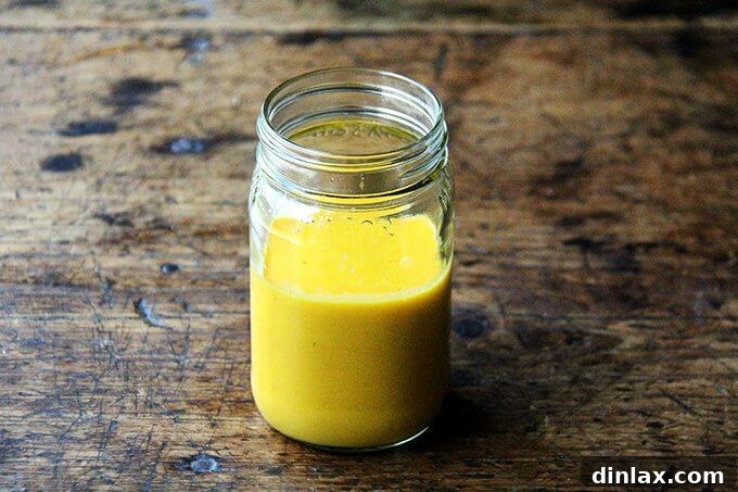 A glass bottle filled with the freshly prepared, golden-orange carrot-miso dressing, ready to be drizzled over a delicious salad.