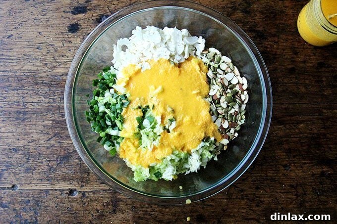 The bowl of assembled cabbage slaw ingredients, now beautifully coated in the creamy miso-carrot dressing, ready for a final toss and serving.