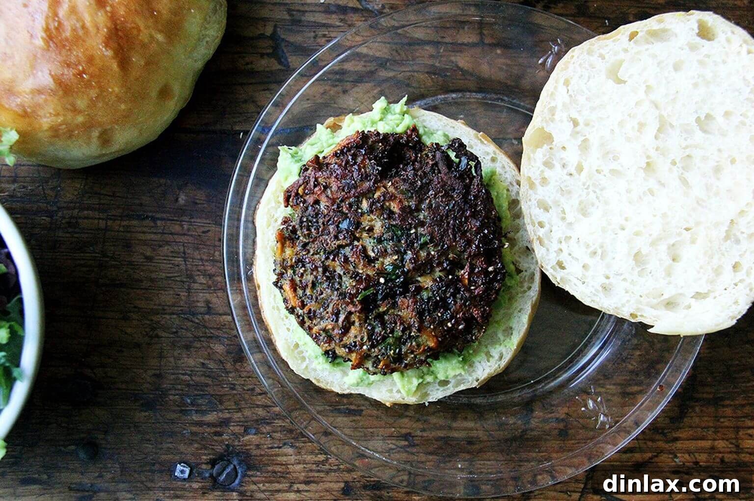 An overhead shot of an open-face veggie burger, showcasing a golden patty nestled on a brioche bun with a generous layer of mashed avocado, inviting diners to take a bite.