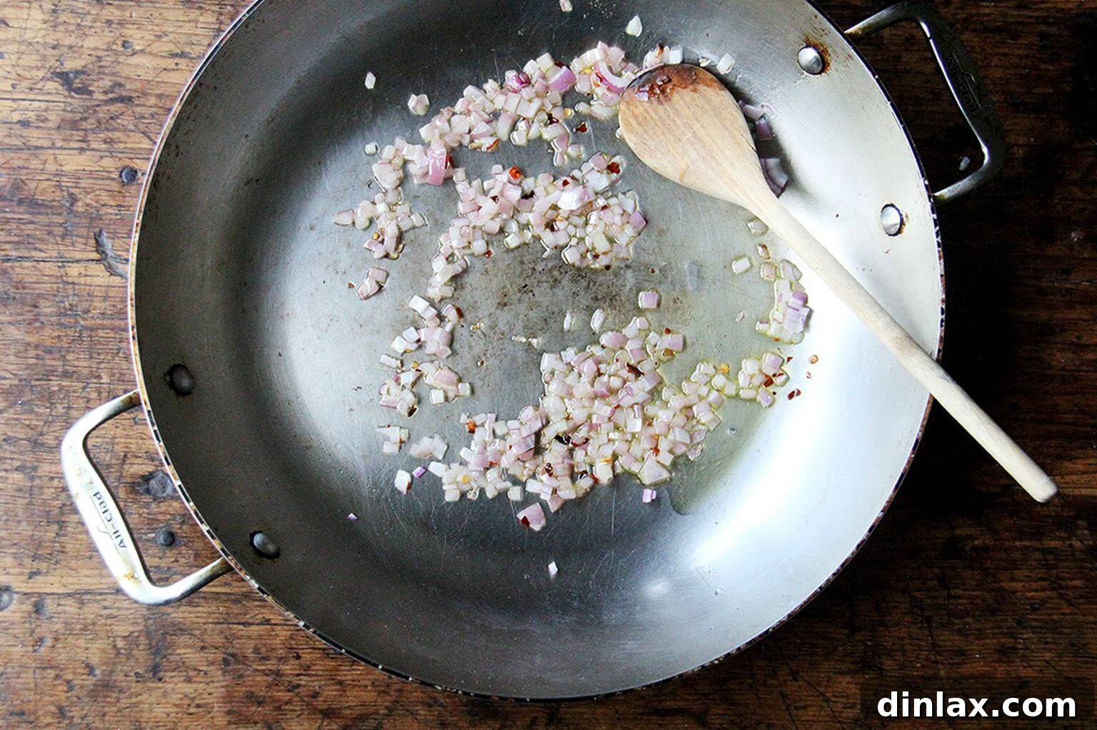 A close-up shot of a shallot or onion sizzling gently in olive oil in a skillet, filling the kitchen with a warm, inviting aroma.