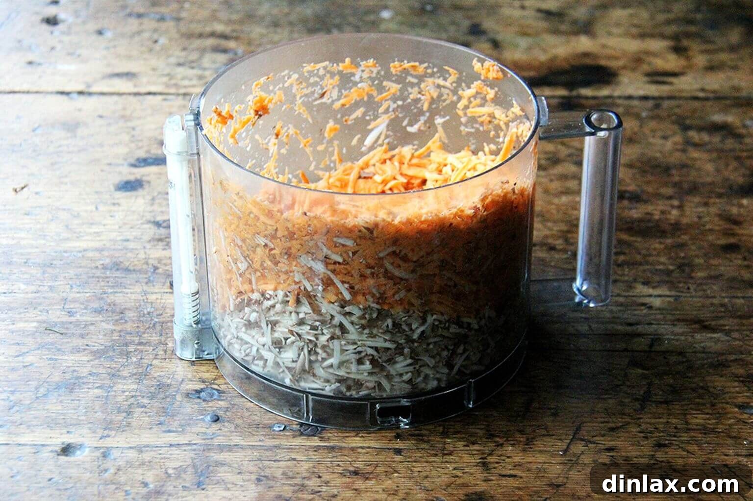 A food processor bowl filled with perfectly grated mushrooms and sweet potatoes, showcasing the efficiency of modern kitchen tools for veggie burger prep.
